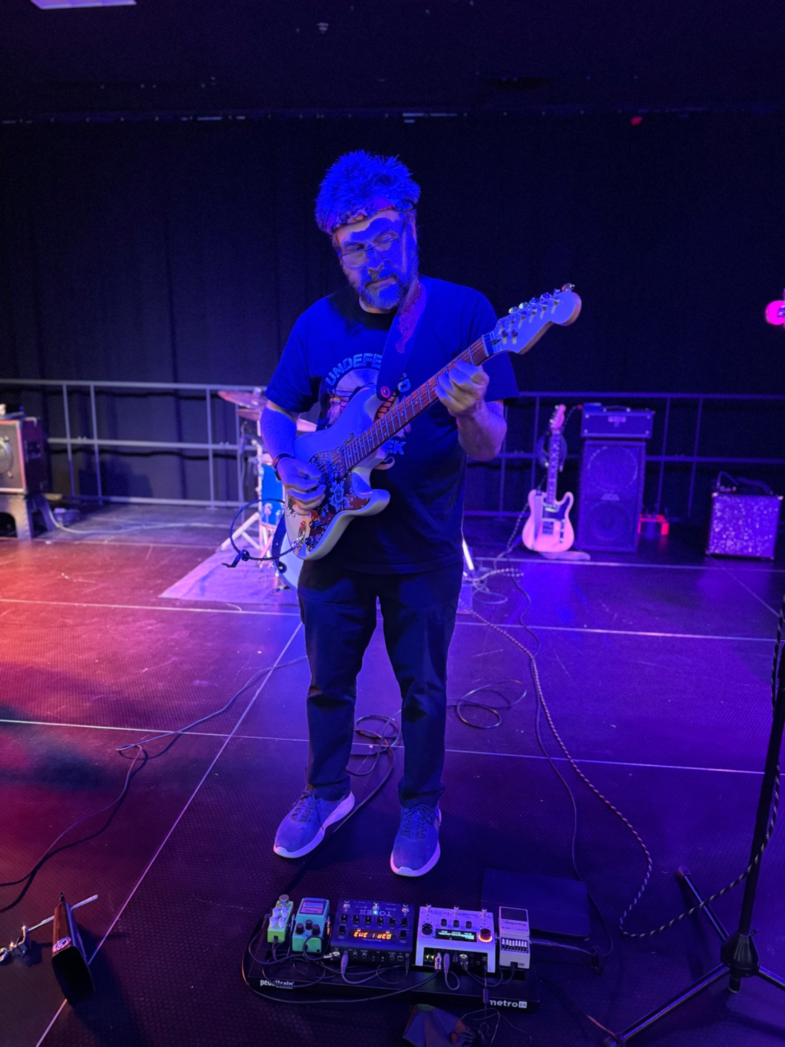 A guitarist playing on stage under blue lighting.